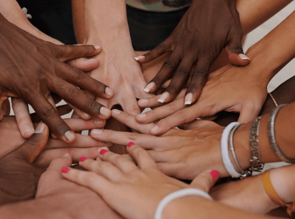 Group of arms extended and hands meeting in centre